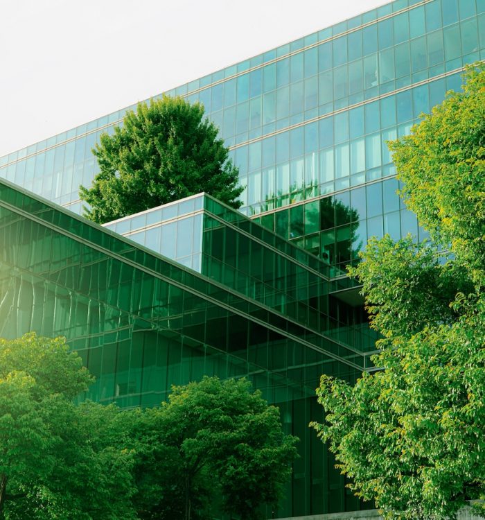 Sustainble green building. Eco-friendly building. Sustainable glass office building with tree for reducing carbon dioxide. Office with green environment. Corporate building reduce CO2. Safety glass.